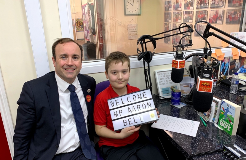 Aaron at Seabridge Radio with his interviewer, who is holding a sign saying "welcome to our MP"