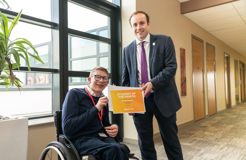 Aaron is handing a certificate to a man in a wheelchair